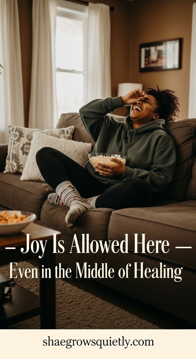 Photorealistic image of a golden-umber-skinned Black woman laughing deeply on her couch with popcorn and cozy textures — capturing emotional healing after burnout through the return of joy and lightness.